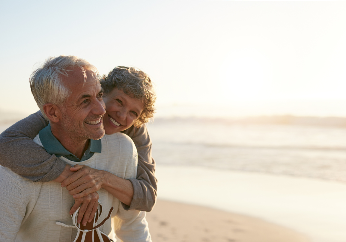 An older couple dancing together by the sea